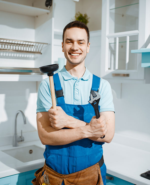 Cheerful male plumber holds wrench and plunger